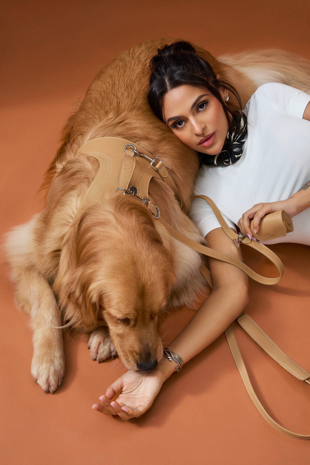 Guia ARIA na cor caramelo em uso, com o cachorro deitado ao lado da tutora